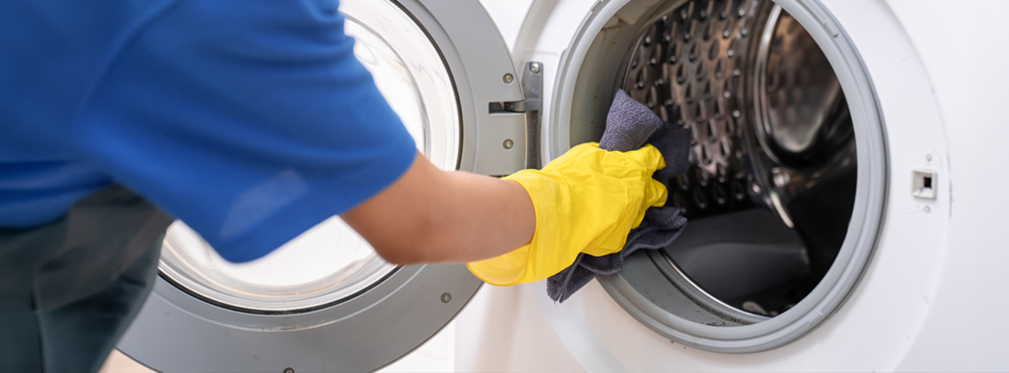 woman cleaner put dirty clothes to washing machine in house