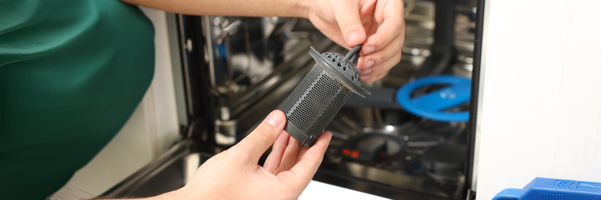 man maintaining dishwasher with filter in hands