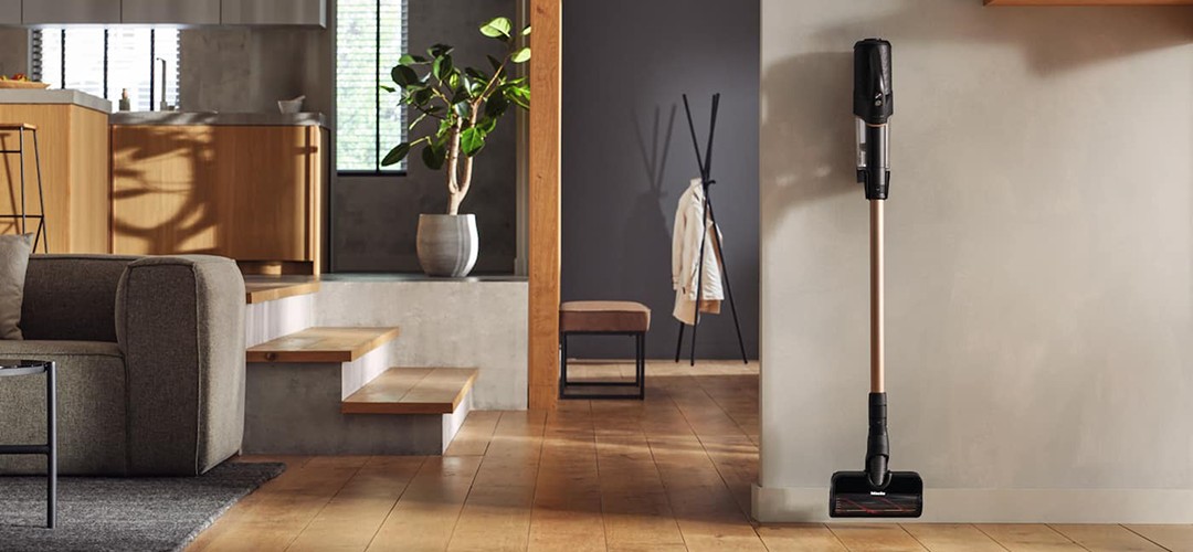 Belaidis dulkių siurblys pastatytas svetainėje prie sienos.