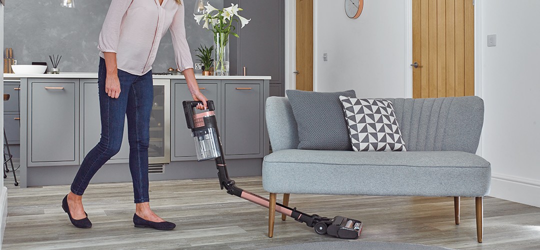 Moteris siurbia grindis belaidžiu dulkių siurbliu svetainėje